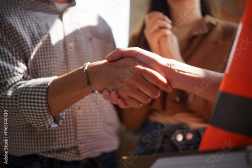 Homeowner shaking hands with a construction engineer after agreeing on a new house building project.