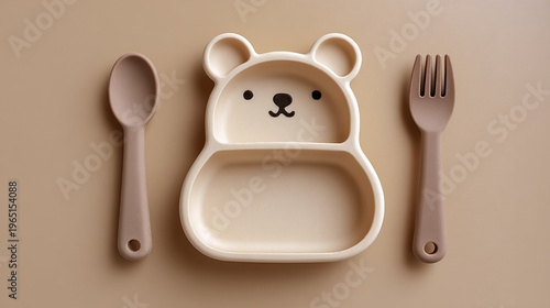 Baby feeding accessories. First safe bear shaped plate, fork, spoon, bib. Silicone tableware, cutlery set on beige neutral background. Kids dishware concept. Serving child food. Solid color backdrop