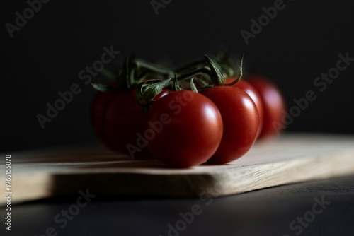Foto Dramatic close up of ripe cherry tomatoes on wooden cutting board with moody lighting for gourmet culinary advertising and editorial design