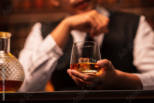 Bartender Holding a Glass of Premium Whiskey on Bar Counter