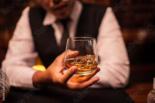 Bartender Holding a Glass of Premium Whiskey on Bar Counter