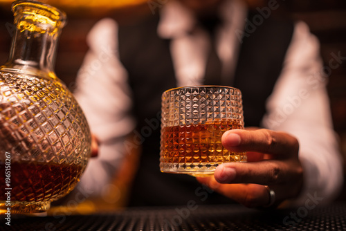 Bartender Holding a Glass of Premium Whiskey on Bar Counter