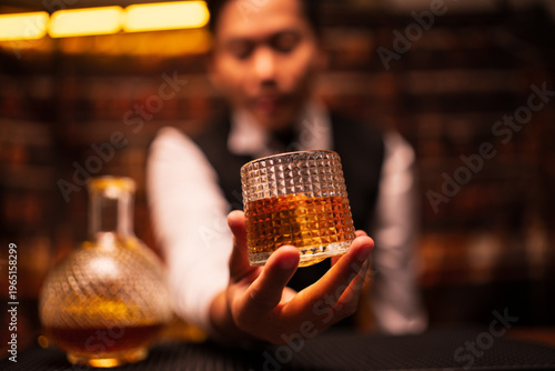 Bartender Holding a Glass of Premium Whiskey on Bar Counter