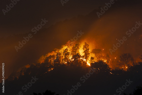 Foto Devastating wildfire smoke pollution and fire burning across dark mountain fores