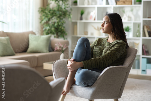 Photos Woman sitting in armchair looking away relaxing at home