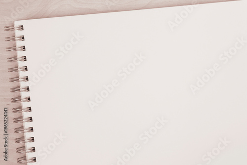blank page of sketchbook with spiral binder laying on wooden board