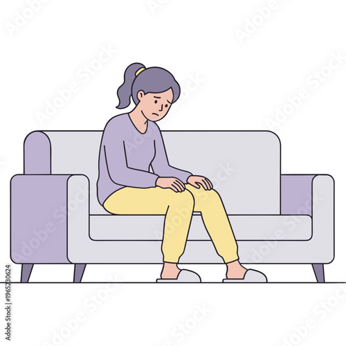 A woman sits on a couch, looking down at her lap with a concerned expression.