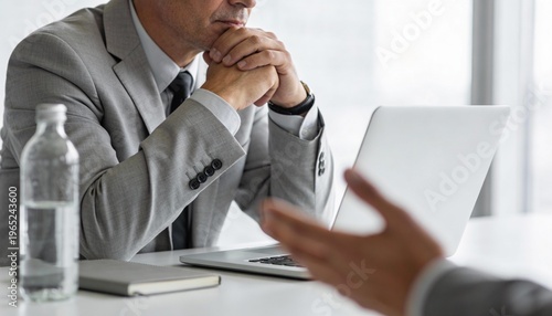 Businessman thinking during meeting using laptop in modern office setting
