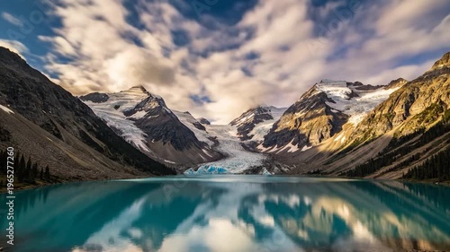 A stunning glacial lake reflects majestic snow-capped mountains under a dramatic cloudy sky