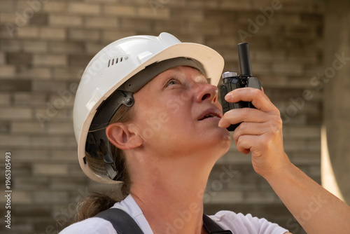 Worker uses radio to communicate during construction at a building site in the afternoon