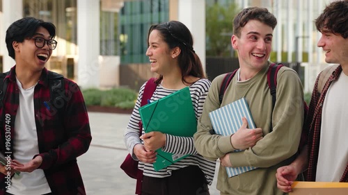 Multicultural University students walking together carrying notebooks, outdoor urban campus lifestyle