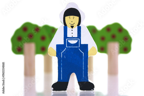 Toy farmer in front of toy trees on a white background
