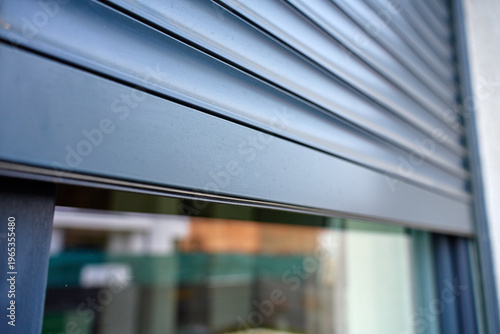 Fotografie Close up of modern metal roller shutter partially covering window on building exterior