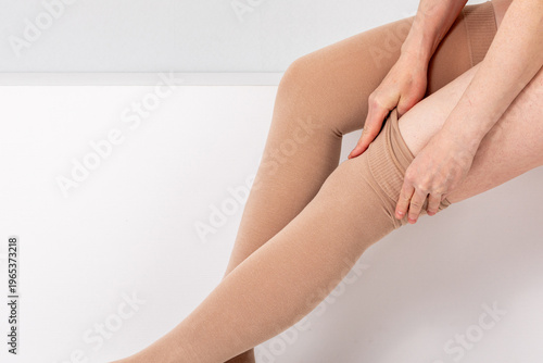 Obraz na plátně Woman putting on compression stockings to treat varicose veins and leg edema