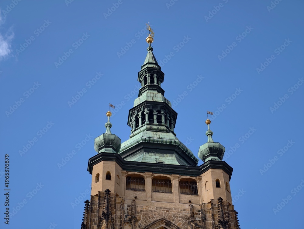 Fototapeta premium Gilded finial atop copper structure shines. Architectural cupola with detailed patina under clear skies