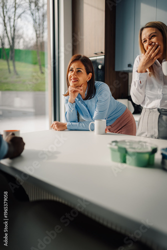Businesswomen enjoying coffee break and conversation in office kitchen