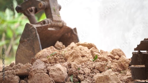 Earth Mover at Work: An earth mover's metallic scoop plunges into a pile of dirt in an outdoor construction project, highlighting the industry's essential activity. 