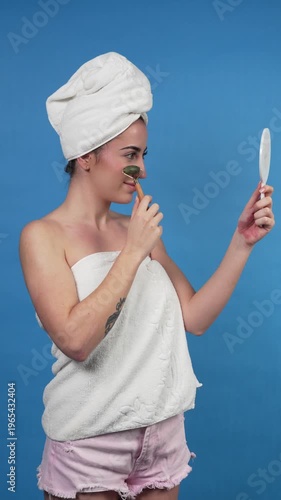 Young woman using jade roller for facial massage