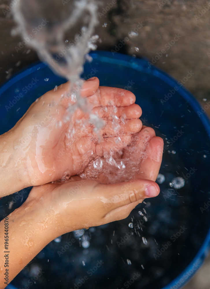 Fototapeta premium The water flows into the hands of the child. Selective focus.