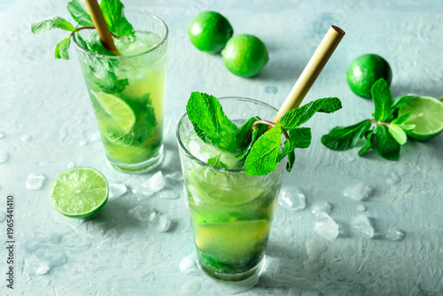 Mojito, summer cocktail with mint and ice, with fresh limes, with a straw