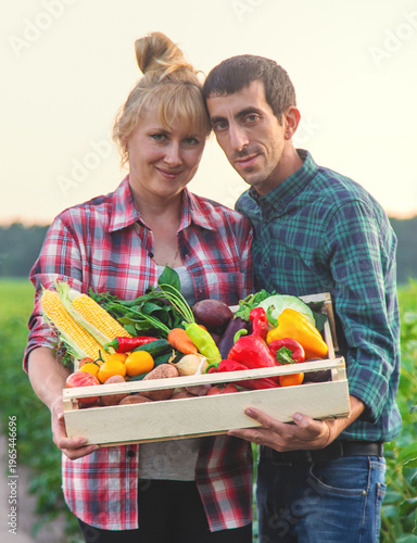 A woman and a man farmer are holding vegetables in their hands. Selective focus.
