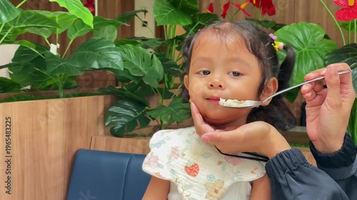 Little girl grimaces and refuses to eat that her mom feeds her.