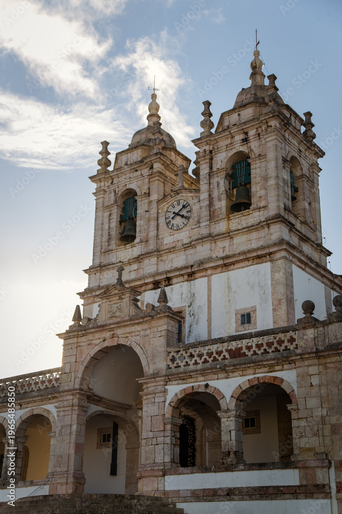 Fototapeta premium Historic Stone Church with Bell Towers Against Blue Sky