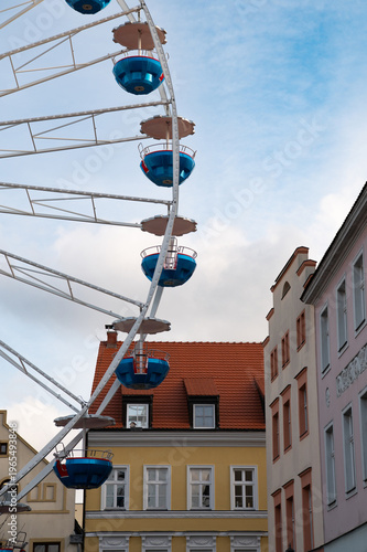 Ferris wheel in Cottbus, Germany with colorful houses and urban architecture under blue sky