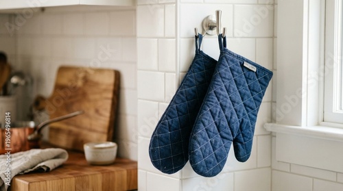 Quilted navy blue oven mitts hanging in modern kitchen interior  