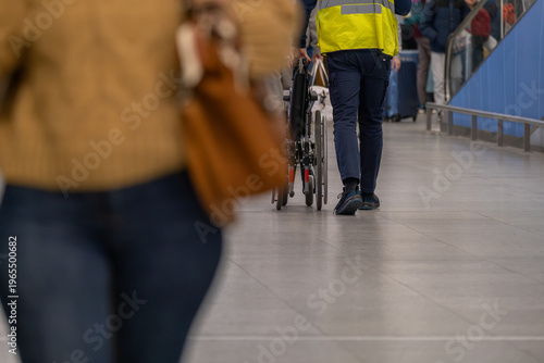 Airport staff pushing wheelchair in terminal, passenger assistance service