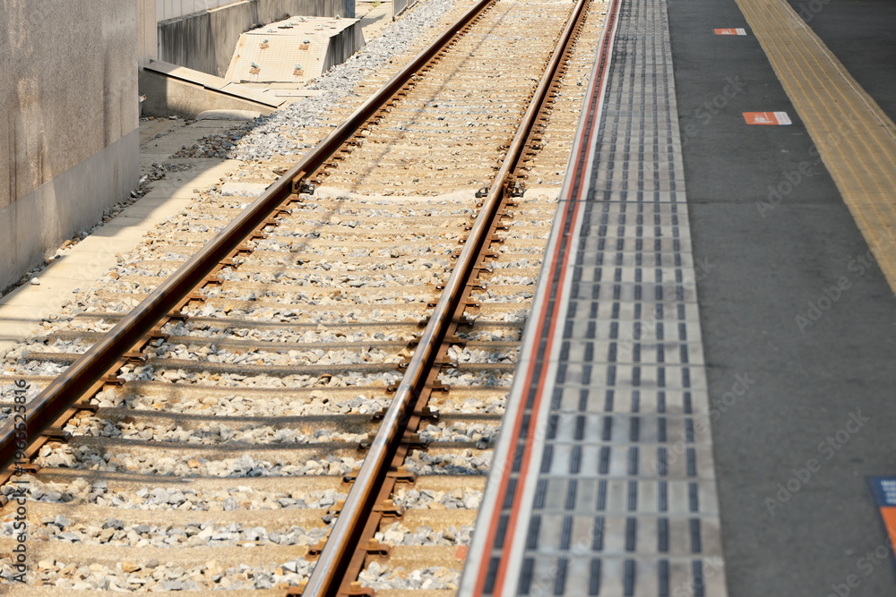 Fototapeta premium 鉄道駅のホーム縁と線路のクローズアップ 公共交通インフラ、通勤の日常、安全と境界線を象徴するコンセプトイメージ