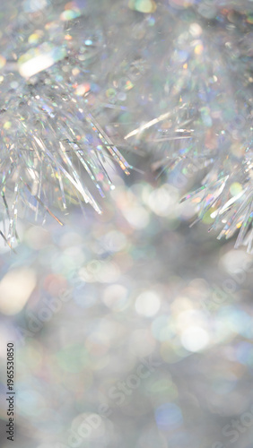 Close-up of shimmering silver tinsel with colorful reflections and blurred background for festive decoration