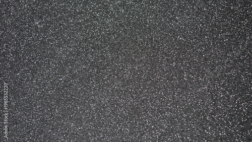 Textured black surface with fine glitter particles creating a shimmering effect