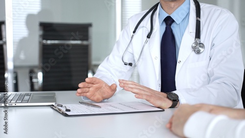Foto Male doctor communicating with patient at a clinic desk, offering professional healthcare guidance and explaining a diagnosis