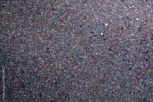 Shimmering glitter texture background with colorful specks on dark surface for creative design