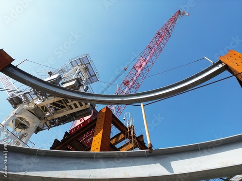 Tablou pe pânză Curved steel beams and tower cranes at a construction site.