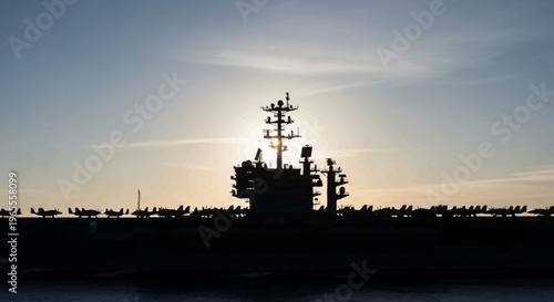 Silhouette of a Military Aircraft Carrier with Fighter Jets on Deck at Sunset