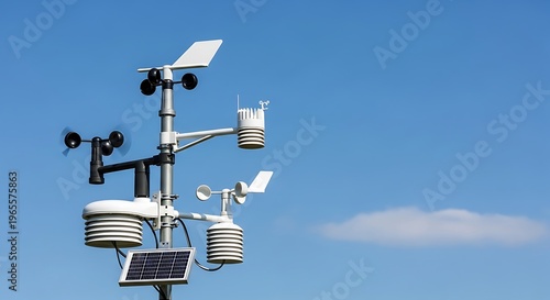 A detailed image of a meteorological weather station measuring conditions against a bright blue sky. The equipment features wind vanes, solar panels, and thermometers.