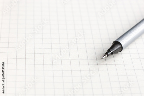 Silver pen resting on blank graph paper with grid pattern