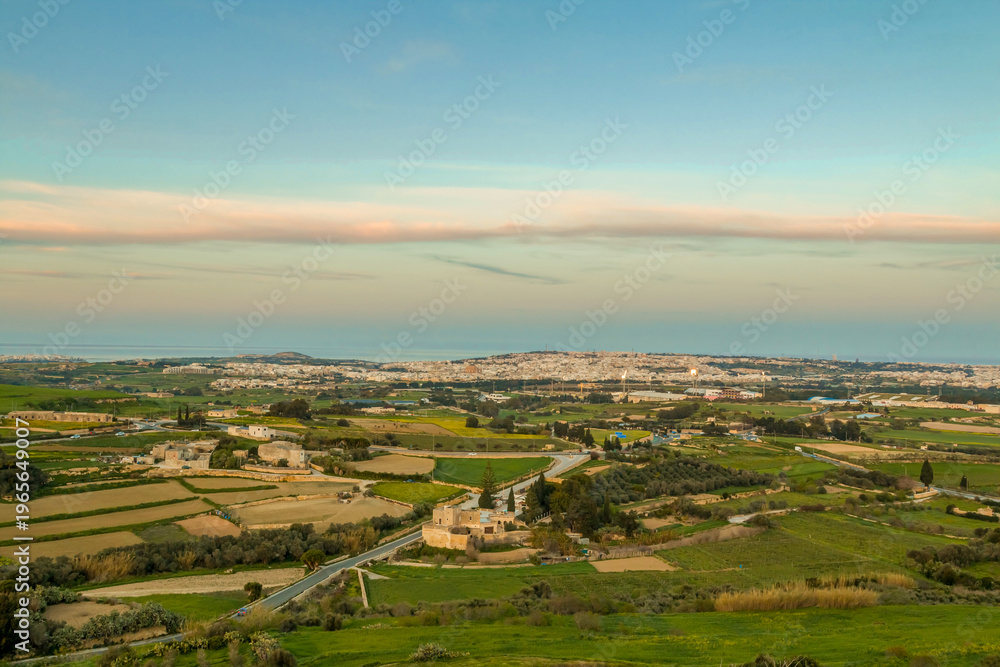 Fototapeta premium View from the Mdina fortifications in Malta overlooking the surrounding landscape at sunset, with golden light, distant views, and a peaceful panoramic scene from the scenic viewpoint.
