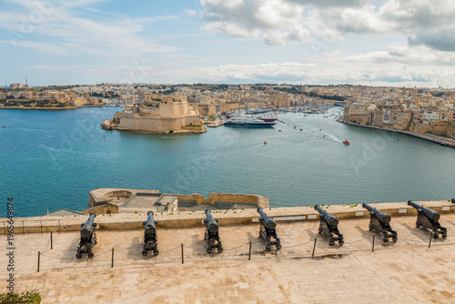 Tableau sur toile View of the cannon-lined square in Valletta, Malta, overlooking the Three Cities – Isla, Birgu, and Kalkara – with historic architecture and scenic harbor views