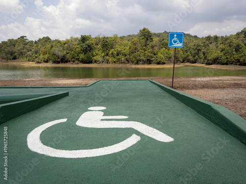Wheelchair accessible ramp with disability symbol near lakeside, barrier-free access in natural outdoor setting, inclusivity and accessibility concept