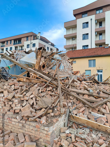 Old house being demolished in the foreground while modern apartment buildings rise in the background, symbolizing progress and redevelopment