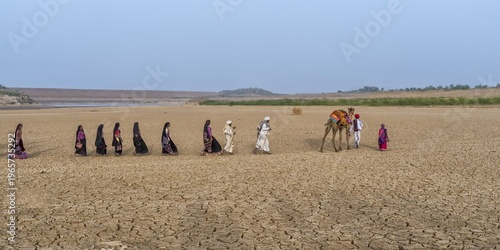 Rabari tribe people walking in the desert with a dromedary, Great Rann of Kutch, Gujarat, India