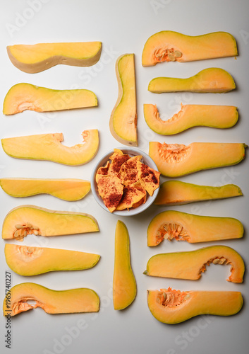 Autumn superfood. Raw and dehydrated crispy pumpkin chips in bowl and white background. Product presentation