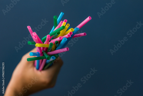 Close up of hand holding bamboo straws on blue background