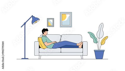 Young man relaxing on a comfortable gray sofa while working on a laptop computer in a stylish modern living room with a floor lamp.