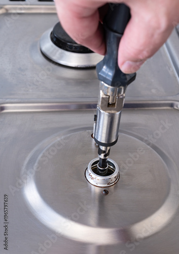 Man fixing an gas nozzle or burner orifice with a tool