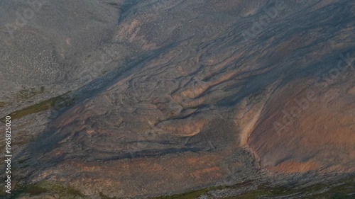 Aerial view of rocky tundra slope near Penkigney Bay, Provideniya area. Chukotka, terrain shows layers and erosion in warm evening light. The drone hovers with slight drift to scan the hillside
