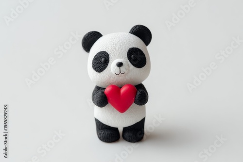 Cute panda figurine holding red heart on white background